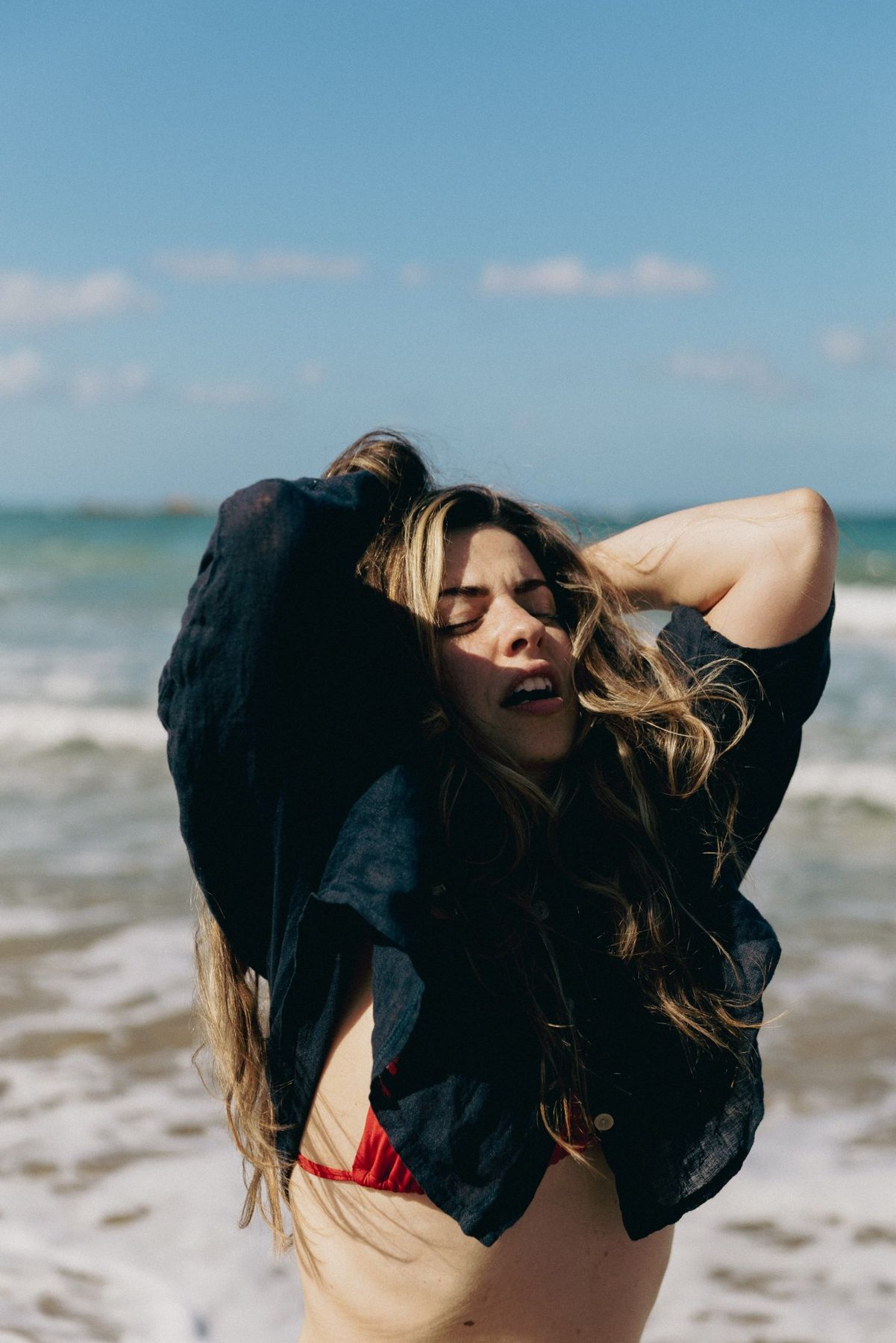 Lucia by the sea, head tilted back in release, arms lifted