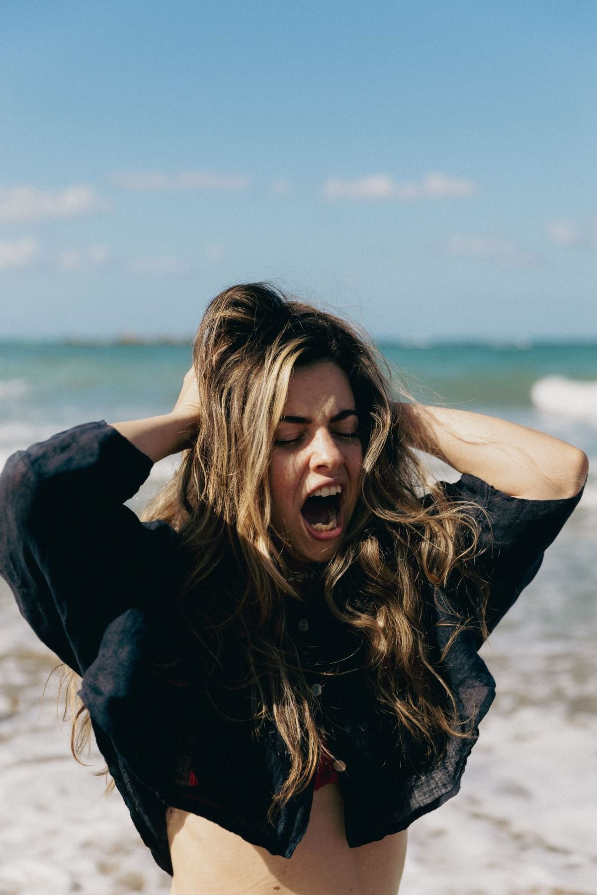 Lucia screaming on the beach, hands in her hair