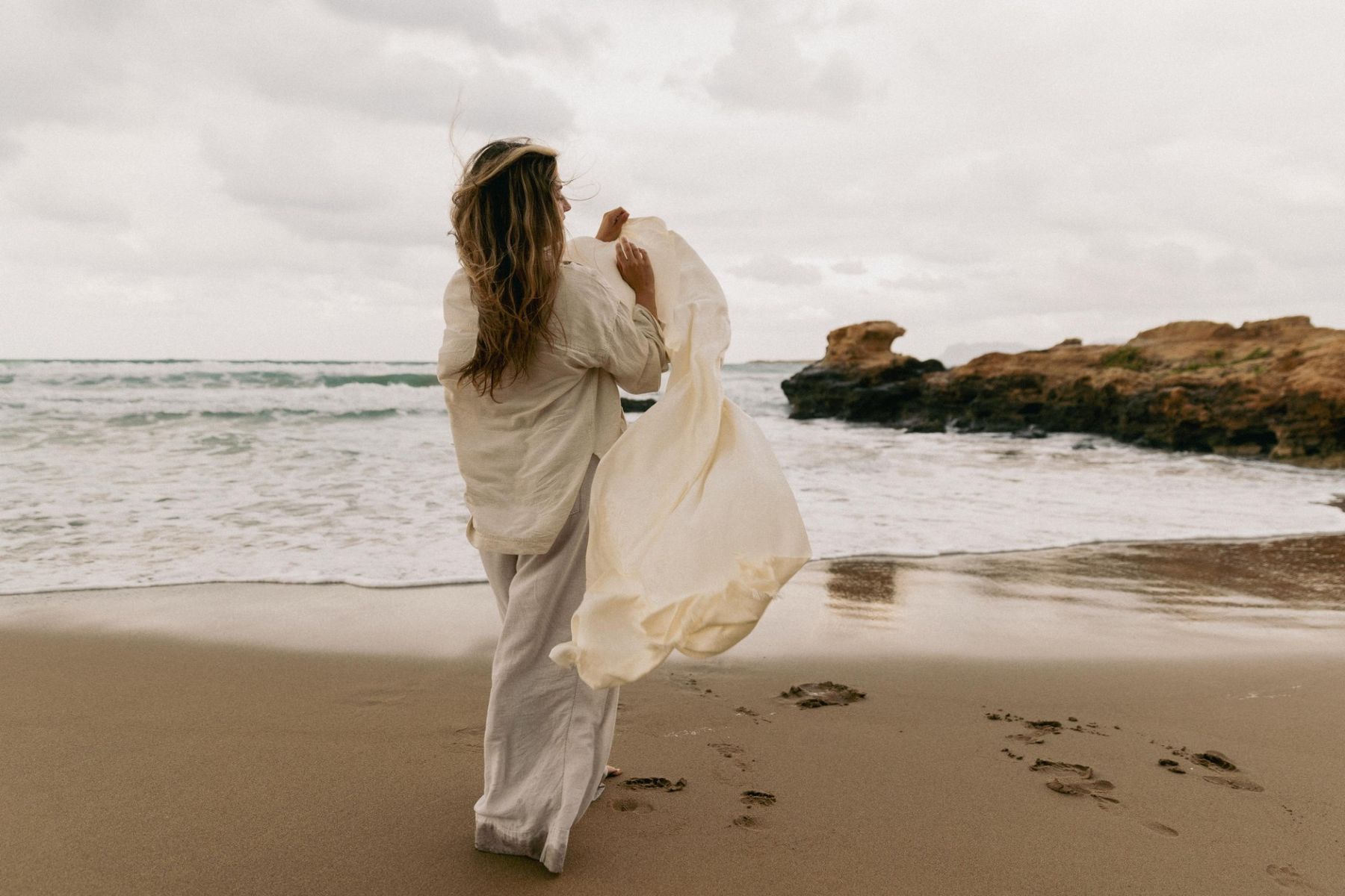 Lucia by the sea, eyes closed, long hair falling over her shoulders